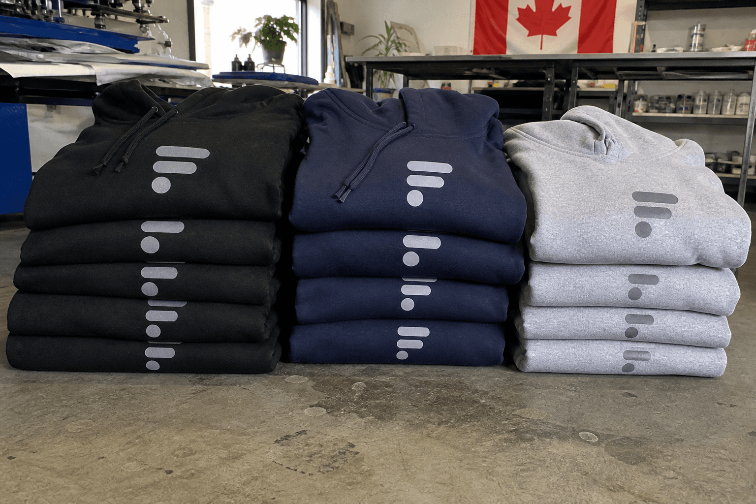 Stacks of custom hoodies and apparel in a Calgary print shop